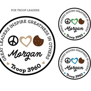 May include: Circular design with the text "GREAT LEADERS INSPIRE GREATNESS IN OTHERS." The design includes a peace symbol, a heart, and a cookie. The name "Morgan" and "Troop 3960" are also included.