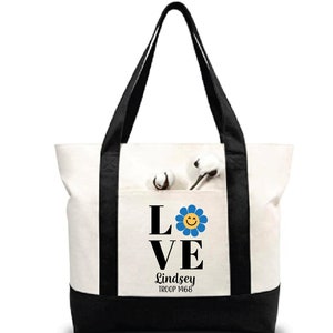Pu&ograve; includere: Borsa tote in tela bianca con manici neri e fondo nero. La borsa ha una tasca sul davanti con un fiore nero e blu con un'emoticon gialla sorridente. Il testo "LOVE" &egrave; in lettere nere sopra il fiore e il testo "Lindsey TROOP 1468" &egrave; sotto il fiore.