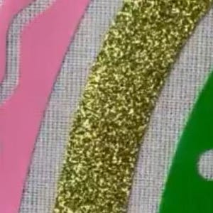 以下が含まれることがあります： 装飾要素のあるテクスチャードファブリックのクローズアップ。金色のキラキラしたストライプ、ピンクの波状の形、穴のある緑色の形が特徴です。デザインは明るい灰色の背景に設定されています。