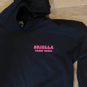 May include: Black hooded sweatshirt with pink lettering that reads "Briella Troop 20226".