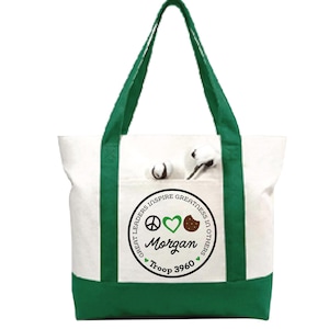 May include: White tote bag with green accents, including the handles and base. The bag features a pocket with cotton bolls and a circular emblem with the text "Great Leaders Inspire Greatness in Others," the name "Morgan," and "Troop 3960."