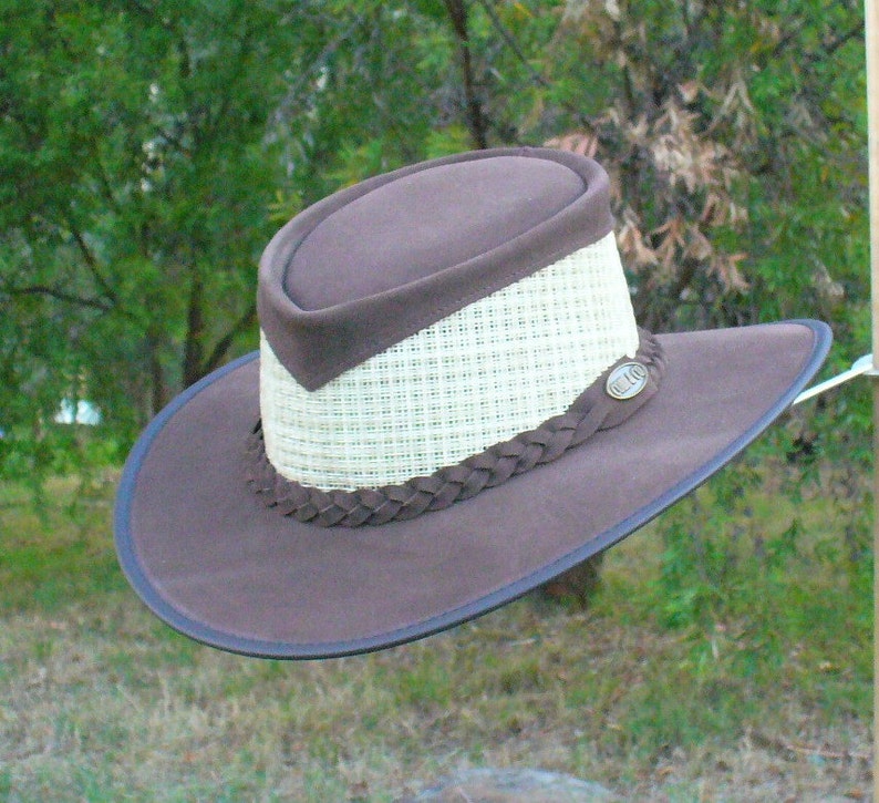 Peut inclure: Un chapeau outback en cuir marron avec une couronne en paille tress&eacute;e et une bande en cuir. Le chapeau a une bordure en cuir marron et une petite &eacute;tiquette m&eacute;tallique avec le texte "B.L.A.C."