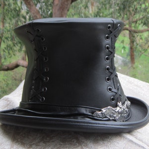 May include: A black leather top hat with a lace-up detail and a silver bat design on the brim.