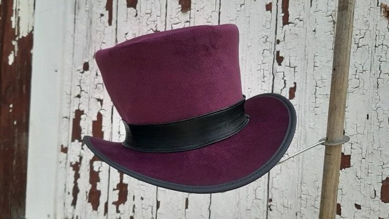 May include: A purple top hat with a black band around the crown. The hat is made of felt and has a wide brim.