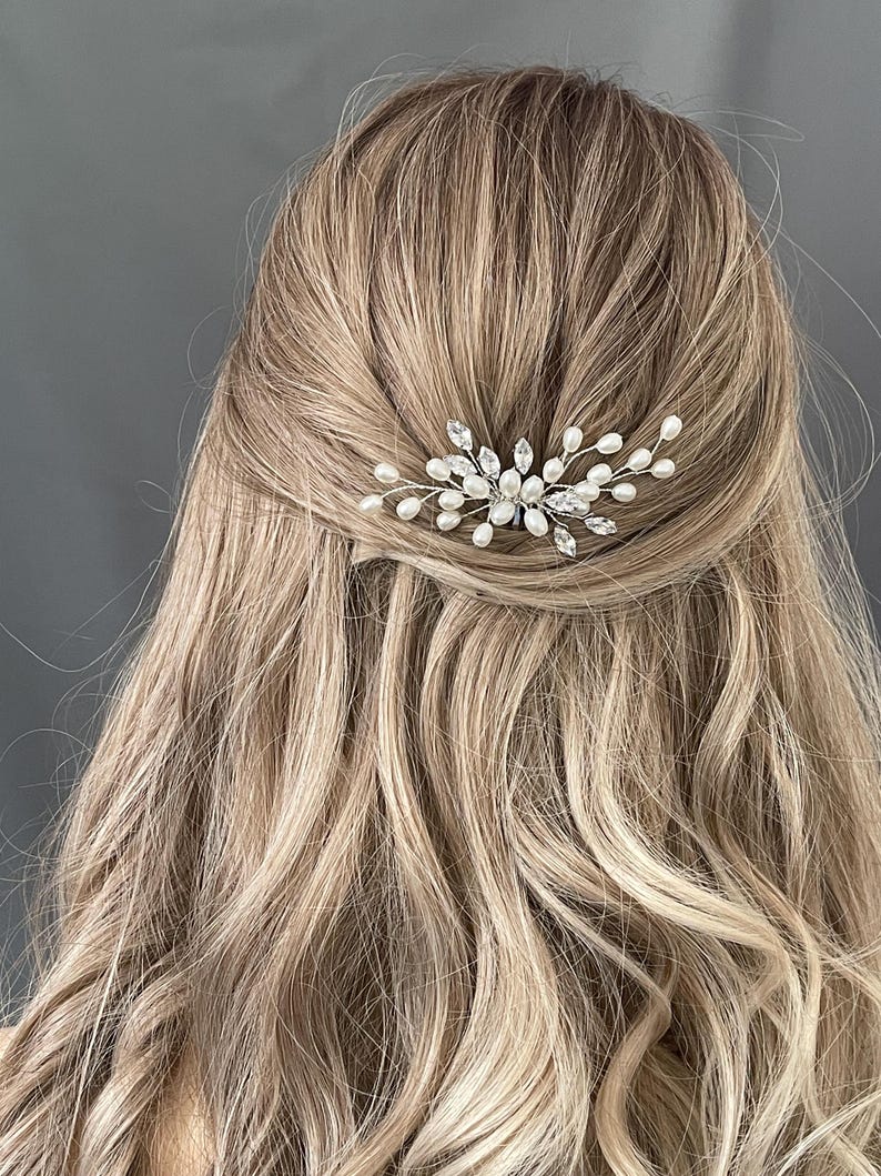 May include: A silver hair comb with pearl and crystal accents. The comb is designed in a delicate, floral pattern.