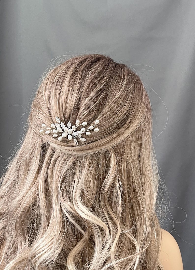 May include: A silver hair comb with pearl and crystal accents. The comb is designed to look like a delicate branch with leaves and pearls.