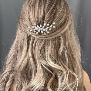 May include: A silver hair comb with pearl and crystal accents. The comb is designed in a delicate floral shape.
