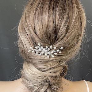 May include: A silver hair comb with pearl and crystal accents. The comb is designed with a delicate, floral-inspired pattern.
