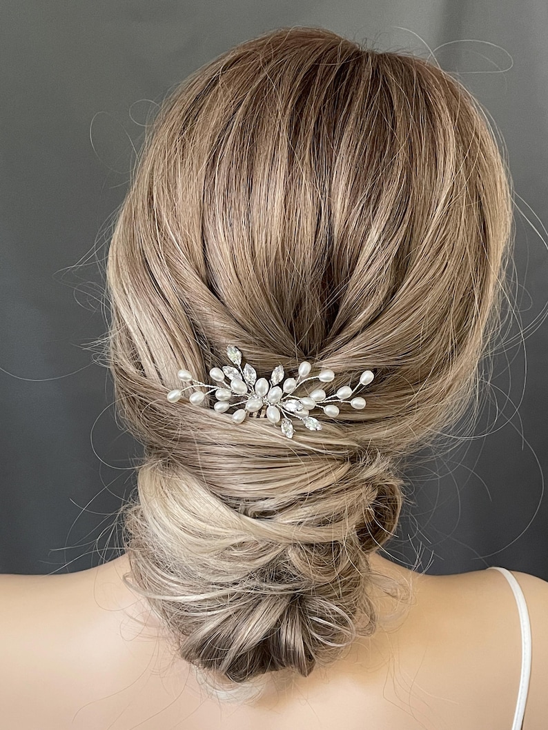 May include: A silver hair comb with pearl and crystal accents. The comb is designed with a delicate, floral-inspired pattern.