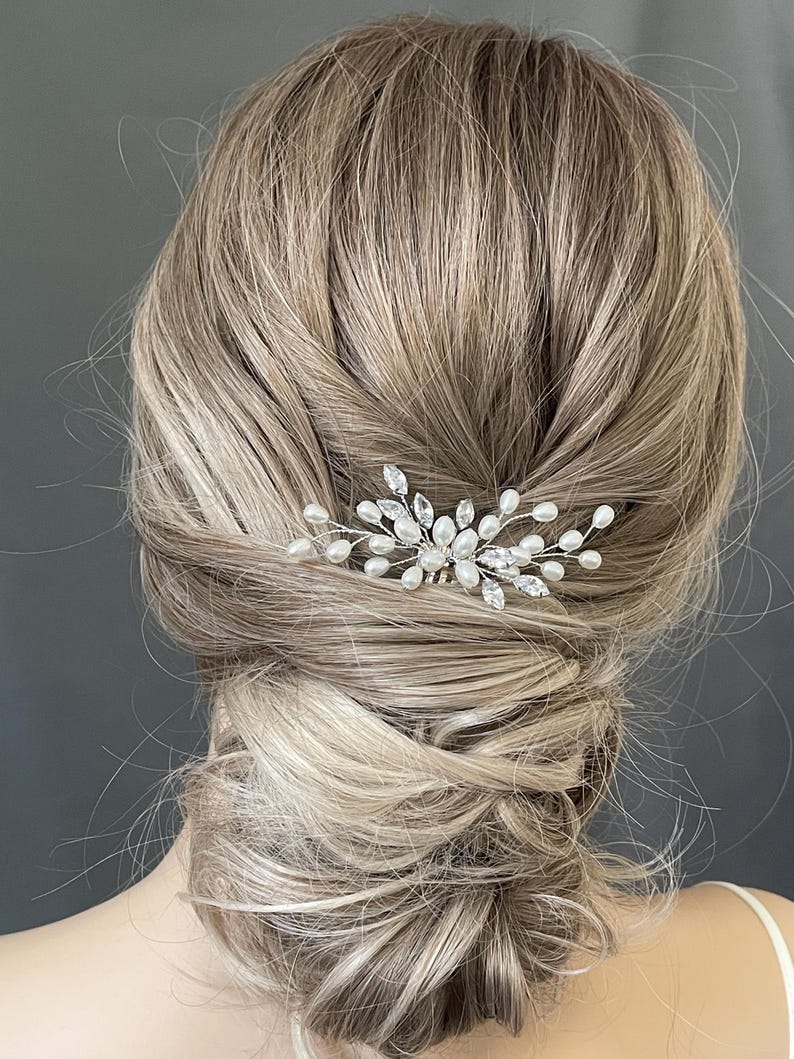 May include: A silver hair comb with pearl and crystal accents. The comb is designed in a floral shape with delicate branches and leaves.