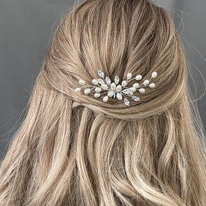 May include: A silver hair comb with pearl and crystal embellishments. The comb is designed in a delicate, floral pattern.