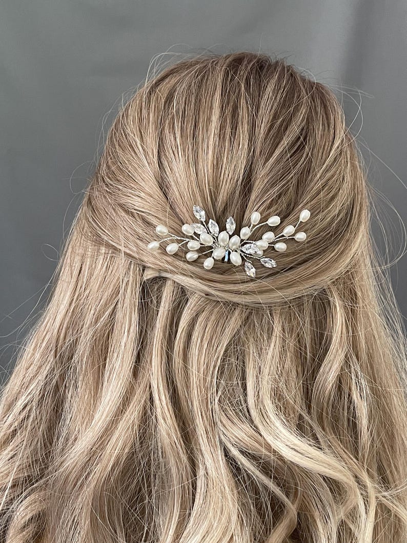 May include: A silver hair comb with pearl and crystal embellishments. The comb is designed in a delicate, floral pattern.