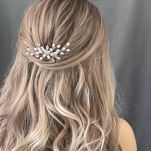 May include: A pair of silver hair clips with pearl and crystal embellishments. The clips are arranged in a delicate, floral design.