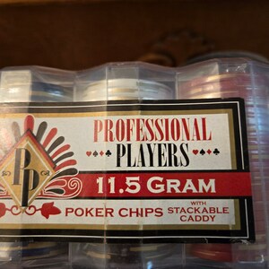 May include: A close-up of a package of 11.5 gram poker chips. The chips are red, white, and blue. The package says "Professional Players" and "with stackable caddy".
