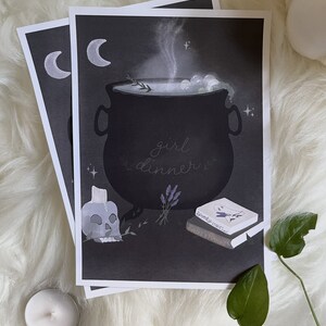 May include: A black and white illustration of a cauldron with steam rising from it. The cauldron is filled with a light blue liquid and has bubbles. The text "girl dinner" is written in cursive below the cauldron. There are two crescent moons in the top left corner of the image. There is a skull with a candle on top of it, a bunch of lavender, and two books with the titles "Spooky Stories" and "Sweet & Potions" in the bottom right corner of the image.