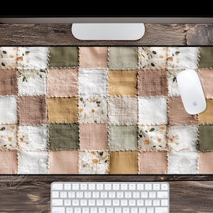 May include: A rectangular mouse pad with a patchwork design in shades of white, pink, green, and tan. A white mouse rests on the pad, with a white keyboard below. The pad has a black border.