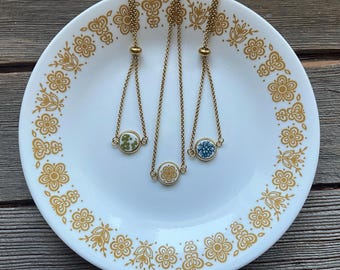 Small Corelle stainless steel bracelets in gold. Stainless steel dangly style bracelet with 12mm broken china setting - 3 patterns available