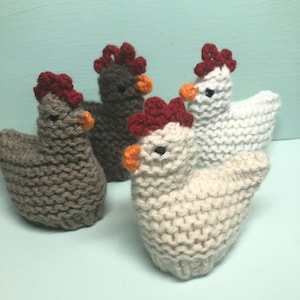 May include: Three knitted chickens, one brown, one white and one beige, with red combs and orange beaks.