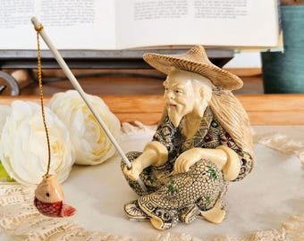 木製の台に置かれたヴィンテージの中国漁師の樹脂製置物、ボートで釣り