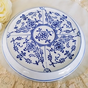 May include: White ceramic plate with a blue floral pattern. The plate has a central floral medallion and a repeating design around the rim. The blue and white colour scheme is reminiscent of traditional Delftware.