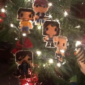 Puede incluir: Un &aacute;rbol de Navidad decorado con adornos hechos a mano de pixel art de personajes de dibujos animados. Los adornos est&aacute;n hechos de fieltro y cuentas y presentan diferentes personajes con diversas expresiones.
