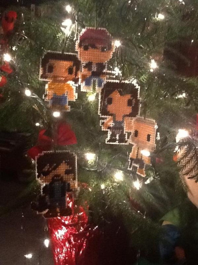 Puede incluir: Un &aacute;rbol de Navidad decorado con adornos hechos a mano de pixel art de personajes de dibujos animados. Los adornos est&aacute;n hechos de fieltro y cuentas y presentan diferentes personajes con diversas expresiones.