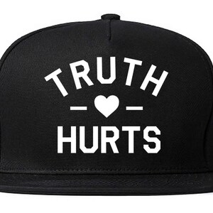 May include: Black and white baseball cap with the text "TRUTH - HEART - HURTS" on the front.