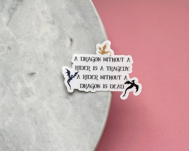 May include: A white sticker with black and gold dragon silhouettes and the text "A dragon without a rider is a tragedy. A rider without a dragon is dead."