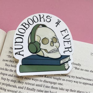 May include: A white sticker featuring a skull wearing headphones and a stack of books. The sticker reads "Audiobooks 4 Ever" in a black and white circular design.