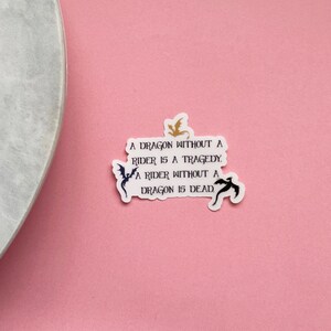 May include: A white sticker with black text and a gold and black dragon silhouette. The text reads "A dragon without a rider is a tragedy. A rider without a dragon is dead."
