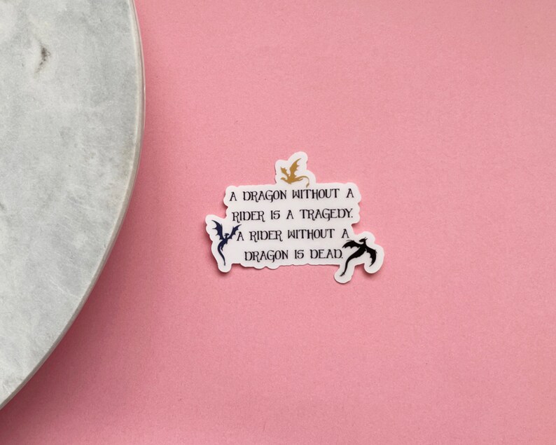 May include: A white sticker with black text and a gold and black dragon silhouette. The text reads "A dragon without a rider is a tragedy. A rider without a dragon is dead."