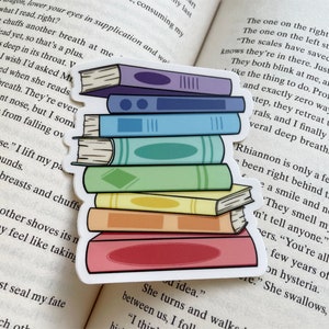 Könnte beinhalten: Ein Aufkleber mit einem Stapel bunter Bücher. Die Bücher sind übereinander gestapelt und haben verschiedene Farben, darunter Lila, Blau, Grün, Gelb und Pink. Der Aufkleber ist perfekt, um Ihrem Planer, Laptop oder Ihrer Wasserflasche einen Hauch von Verspieltheit zu verleihen.