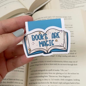 May include: A blue and white sticker with an open book design. The book has stars and the text "BOOKS ARE MAGIC" on the cover.