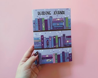 Puede incluir: Un diario de lectura morado con un diseño de estantería que presenta pilas de libros con varios colores y patrones. El texto "READING JOURNAL" está impreso en la portada.