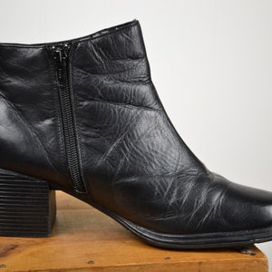 May include: Black leather ankle boots with a chunky heel and a zipper up the back.