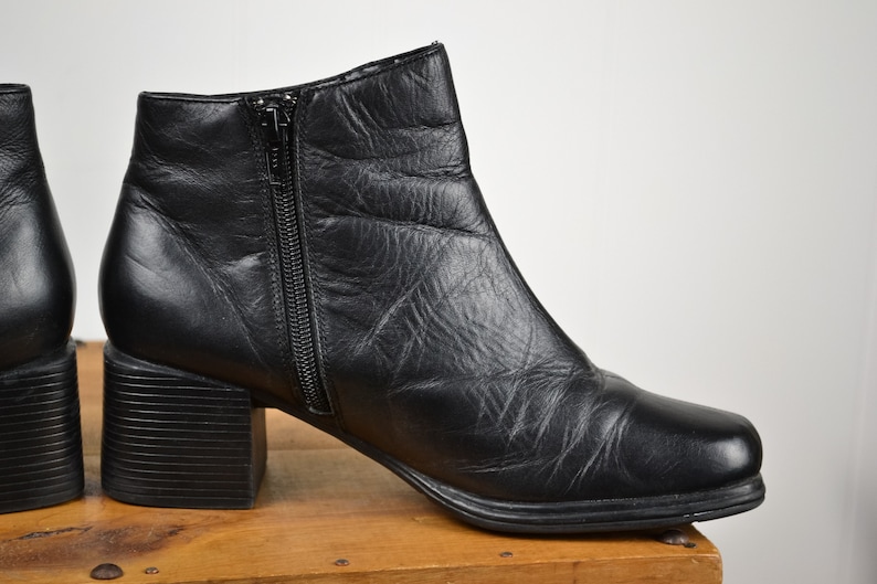 May include: Black leather ankle boots with a chunky heel and a zipper up the back.