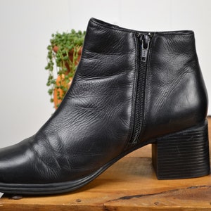 May include: A pair of black leather ankle boots with a block heel and a zipper on the side.