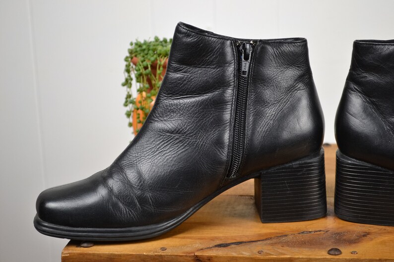 May include: A pair of black leather ankle boots with a block heel and a zipper on the side.