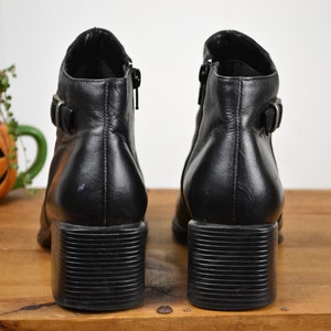 May include: A pair of black leather ankle boots with a chunky heel and buckle detail.