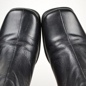 May include: A pair of black leather boots with a square toe and a low heel.