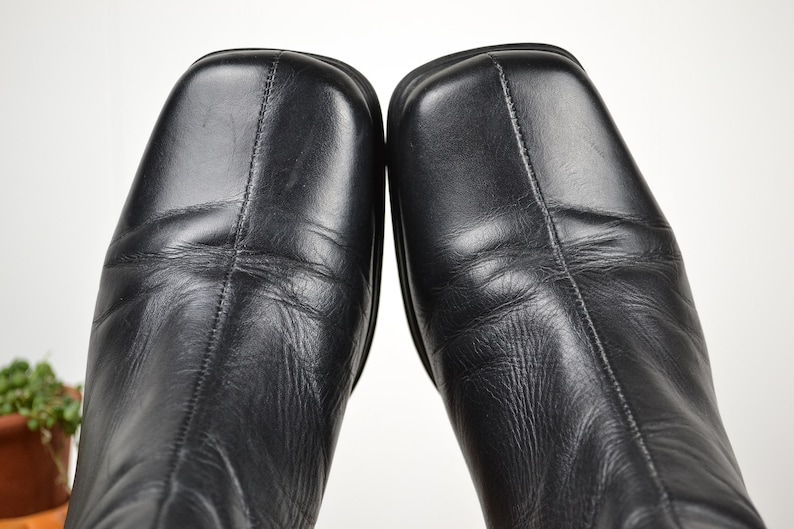 May include: A pair of black leather boots with a square toe and a low heel.