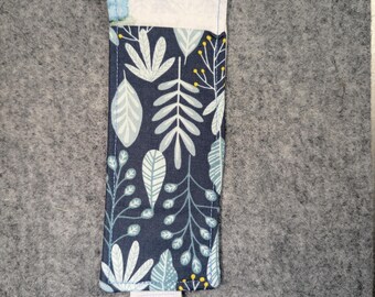 Op de afbeelding: Een rechthoekige stoffen band met een donkerblauwe achtergrond en een herhalend patroon van lichtblauwe en witte bladeren en stengels, geaccentueerd door kleine gele stippen. De band heeft aan de boven- en onderkant een lichtgrijze elastische lus.