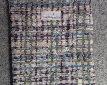 Op de afbeelding: Een rechthoekig gewatteerd tasje met een ruitpatroon in tinten paars, blauw, groen en beige. Het tasje heeft een zwarte rits aan de bovenkant en een wit rechthoekig stoffen label in het midden met de tekst Buddy Buster and Bug.