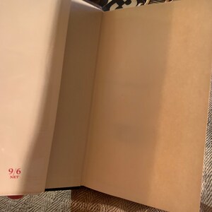 Puede incluir: Primer plano del interior de un libro con una p&aacute;gina en blanco y el n&uacute;mero "9/6" escrito en rojo en la esquina inferior izquierda de la p&aacute;gina.