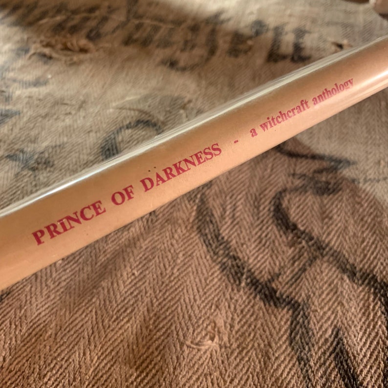 Puede incluir: Primer plano del lomo de un libro titulado "Prince of Darkness - a witchcraft anthology". El t&iacute;tulo est&aacute; impreso en rojo sobre un fondo marr&oacute;n.