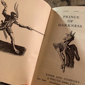 Puede incluir: Una ilustraci&oacute;n en blanco y negro de un demonio sosteniendo un libro. El texto "PRINCE OF DARKNESS" est&aacute; impreso sobre la ilustraci&oacute;n. El texto "RIDER AND COMPANY 47 Princes Gate, London, S.W. MELBOURNE NEW YORK" est&aacute; impreso debajo de la ilustraci&oacute;n.