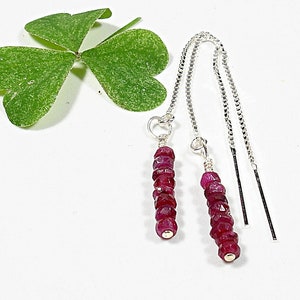 Könnte beinhalten: Ein Paar silberne Ohrringe mit einer Kette und einem Cluster aus roten Rubinperlen.