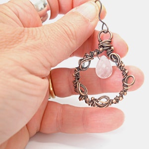 May include: Copper wire wrapped earring with a pink rose quartz gemstone pendant.