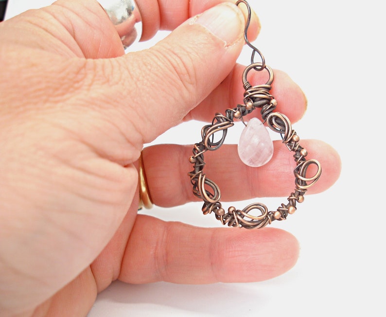 May include: Copper wire wrapped earring with a pink rose quartz gemstone pendant.