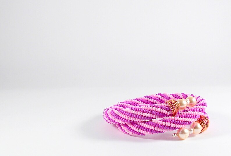 May include: A pink and white beaded necklace with gold wire accents and pearl beads.